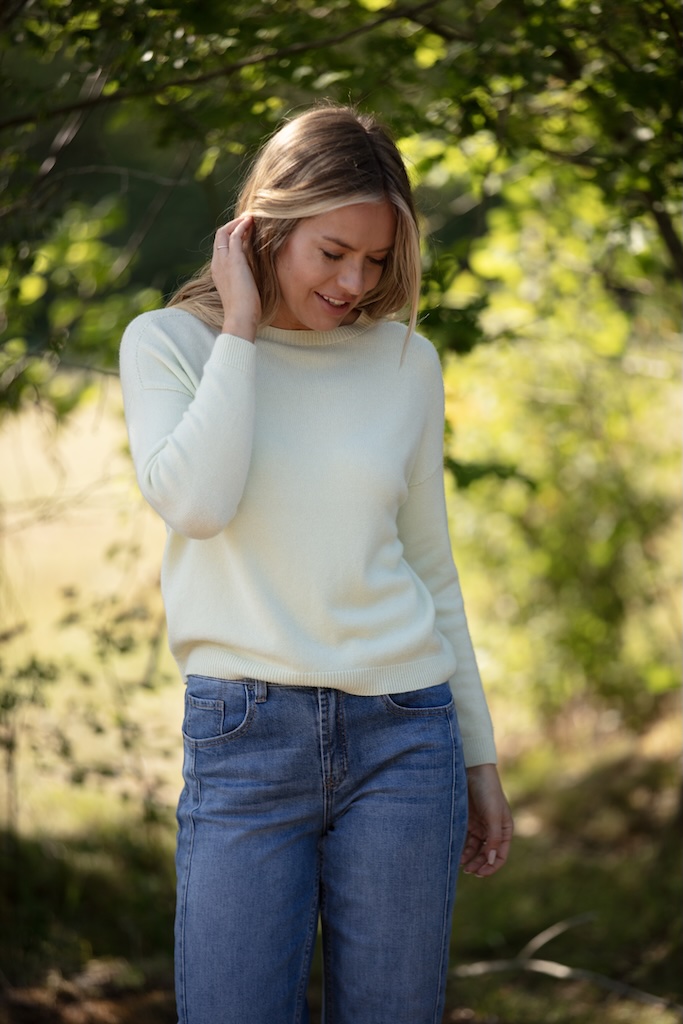 Soft sage lightweight women’s knit jumper styled with blue jeans outdoors